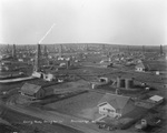 Breckenridge oil field crowded with oil derricks with one oil derrick labeled "R.A. Woods & Comwell Oil Co."; photograph is titled "Getting ready bring her in" by Basil Clemons 1887-1964