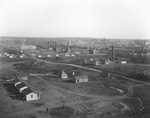 Aerial view of busy oil field with many oil derricks, buildings, and oil tanks on the landscape; photograph is labeled "Texas Pipeline Co." by Basil Clemons 1887-1964