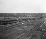 Oil field crowded with oil derricks and train cars parked in foreground; photo labeled "American Oil," near Breckenridge, Texas, ca.1920s by Basil Clemons 1887-1964