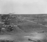 Aerial view of an oil field showing living quarters and office, the B-1 and B-2 oil wells, horse-drawn wagons on the road, and many oil derricks across the landscape by Basil Clemons 1887-1964