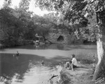 "Lover's Retreat" with people enjoying a bucolic pond surrounded by trees and rocks, Breckenridge, Texas by Basil Clemons 1887-1964