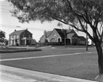 Two upscale brick homes on a tree-lined street; location not identified by Basil Clemons 1887-1964