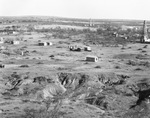 Small settlement of wooden buildings with oil derricks in background, Breckenridge, Texas by Basil Clemons 1887-1964