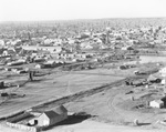 Air view of community of buildings and houses with large oil field nearby, Stephens County, Texas, undated by Basil Clemons 1887-1964