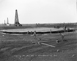 Laying the keel of a 55,000 barrel oil tank with oil derricks in background, undated by Basil Clemons 1887-1964