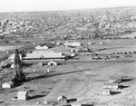 Air view of oil derricks scattered among buildings in the town; Oil Well Supply Co. building near center of photographs by Basil Clemons 1887-1964