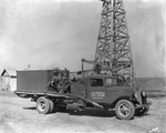 Work truck parked beside an oil derrick and identified as Holder Cementing Co., Oil Well Cementing, Breckenridge, Texas by Basil Clemons 1887-1964