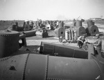 Close-up of oil field tanks and equipment with two oil field workers nearby, location not identified by Basil Clemons 1887-1964