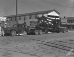 Large oil field equipment pulled by truck parked next to Harper Furniture Hardware building by Basil Clemons 1887-1964