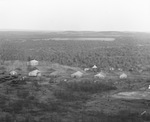 Aerial view of tree covered land with a few wooden buildings in foreground; near oil field, Breckenridge, Texas by Basil Clemons 1887-1964