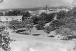 Settlement of buildings and houses among trees with oil wells in far distance, Breckenridge, Texas by Basil Clemons 1887-1964