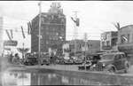 Numerous cars and people on the streets of downtown Breckenridge near the Burch Hotel by Basil Clemons 1887-1964