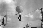 Circus performer holding umbrella and jumping a rope on a tightrope, flanked by three other performers, Breckenridge, Texas by Basil Clemons 1887-1964