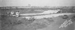 Circus wagons pulled by horses in field near railroad tracks; workers setting up long tents, Breckenridge, Texas by Basil Clemons 1887-1964