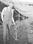 Man holds leash to a monkey sitting on a perch at a traveling circus, Breckenridge, Texas by Basil Clemons 1887-1964