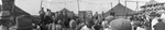 Circus performers stand on outdoor stage in front of large crowd gathered below, Breckenridge, Texas by Basil Clemons 1887-1964