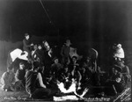 Men and women around a camp fire with one woman holding a baby by Basil Clemons