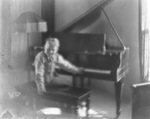 Young boy seated at a grand piano by Basil Clemons 1887-1964