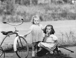 Two young girls with a large tricycle and a wagon by Basil Clemons 1887-1964