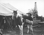 Cowboy Texas Kid mounting a horse, Breckenridge, Texas, 1925 by Basil Clemons 1887-1964