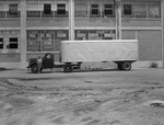 Man standing beside truck with trailer in front of factory (undated) by Bill Wood Photo Company