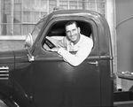 Man leaning out of window of cab of truck with trailer (undated) by Bill Wood Photo Company