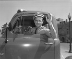 Uniformed police officer in cab of truck, waving by Bill Wood Photo Company