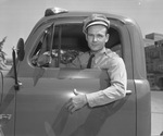 Uniformed police officer in cab of truck with his arm hanging out by Bill Wood Photo Company