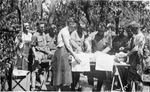 World War I soldiers gathered around wounded soldier on operating table outside in a field