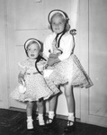 Two children in bonnets and flowered dresses