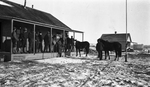 Men standing on a porch, unsaddled horses by Charles M. Davis