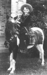 A young Caton boy dressed as cowboy and sitting on a pony