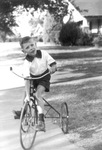 A young Caton boy riding tricycle