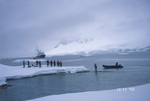 Group on an iceberg with boats in the background in Antarctica. by David Finfrock