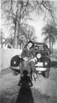 Jack D. White sitting with 2 dogs on the bumper of a black car