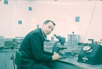 Man at microscope in lab, Carling Brewery