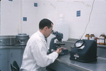 Man working at microscope in lab, Carling Brewery