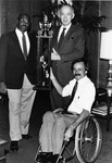 University of Texas at Arlington (U. T. A.) President Dr. W.A. Nedderman presenting trophy to Movin' Mavs wheelchair basketball coach Jim Hayes