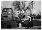 Mattie Mae Capps with little white dog sitting on hind legs in front of home at 1120 Penn Street, Fort Worth, Texas