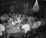 Groups of men eating food at long tables. by Squire Haskins Photography Inc.