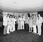 Men and women stand informally in a row. The men are wearing sport jackets and ties, while the women are wearing semi-formal dresses by Squire Haskins Photography Inc.