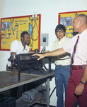 Color photograph of a mechanical arts instructor teaching two male students how to work on a machine part by Squire Haskins Photography Inc.