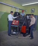 Color photograph of a mechanical arts instructor teaching two male students how to work on a machine part by Squire Haskins Photography Inc.