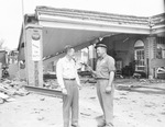 Two men talking in front of a damaged gas station by Squire Haskins Photography Inc.