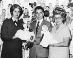 Two women and a man are holding two dolls by Squire Haskins Photography Inc.