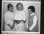 Doris J. Wilson showing diet manual to two women by Squire Haskins Photography Inc.