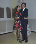 Couple standing in front of a white-flocked Christmas tree by Squire Haskins Photography Inc.