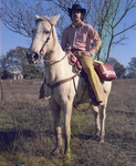 Man sitting on horse in a pasture by Squire Haskins Photography Inc.