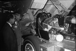 Two men wearing sport coats and ties examine the engine of a semi-tractor. by Squire Haskins Photography Inc.