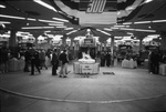 View of a truck and semi-tractor show exhibit hall. An ice sculpture of the Mack Truck bulldog mascot appears front and center. There are men and women looking at the vehicles. by Squire Haskins Photography Inc.